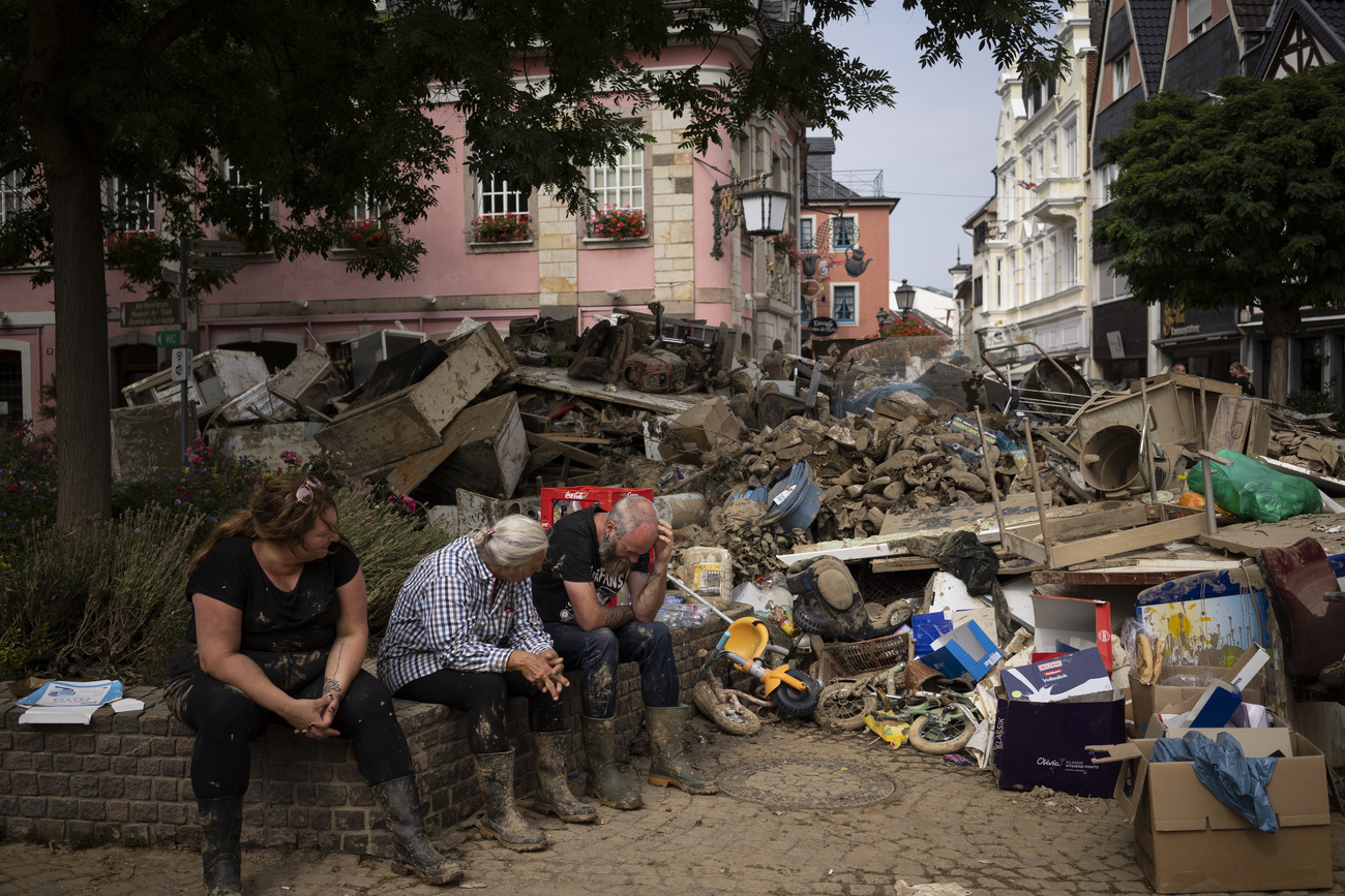 Personas sentadas junto a montones de escombros
