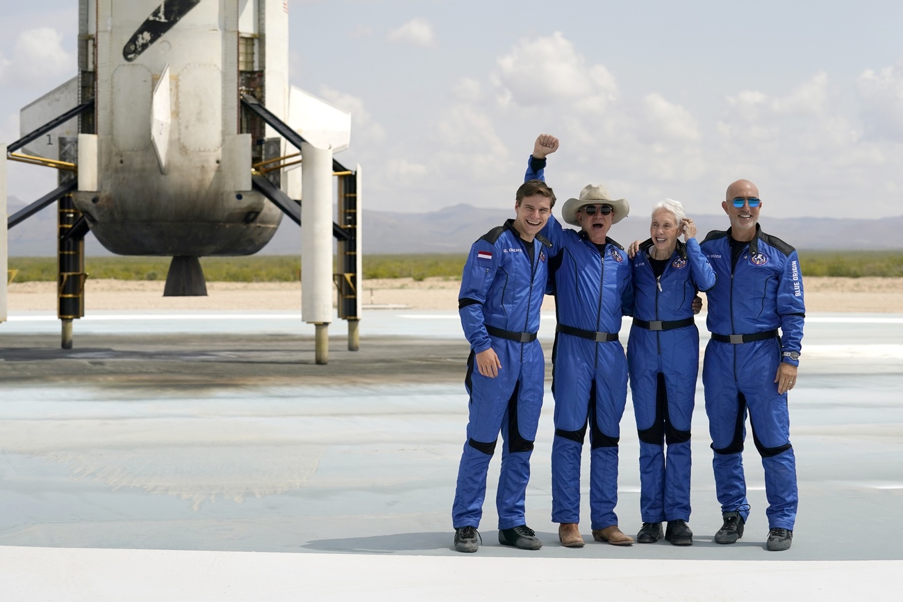 Quattro persone in tuta blu davanti a un velivolo per voli spaziali commerciali