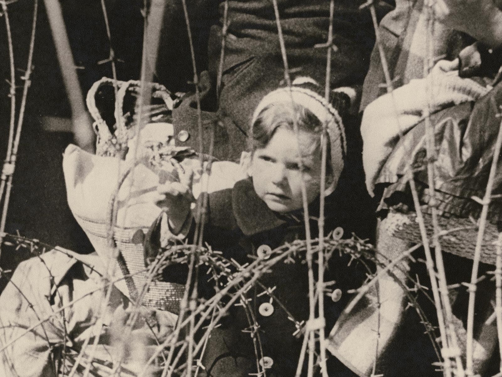 Fotografía antigua de un niño pequeño tras una alambrada.