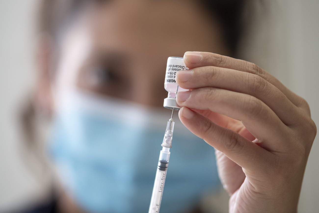 Una mujer introduce un medicamento en una jeringa.