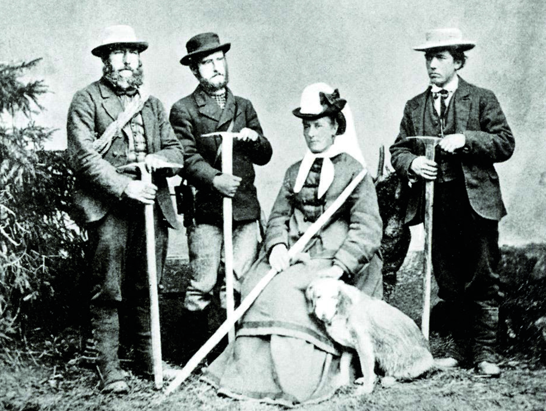 Foto ottocentesca di tre uomini e una donna (lei unica seduta, con accanto un cane) vestiti pesante e armati di piccozza