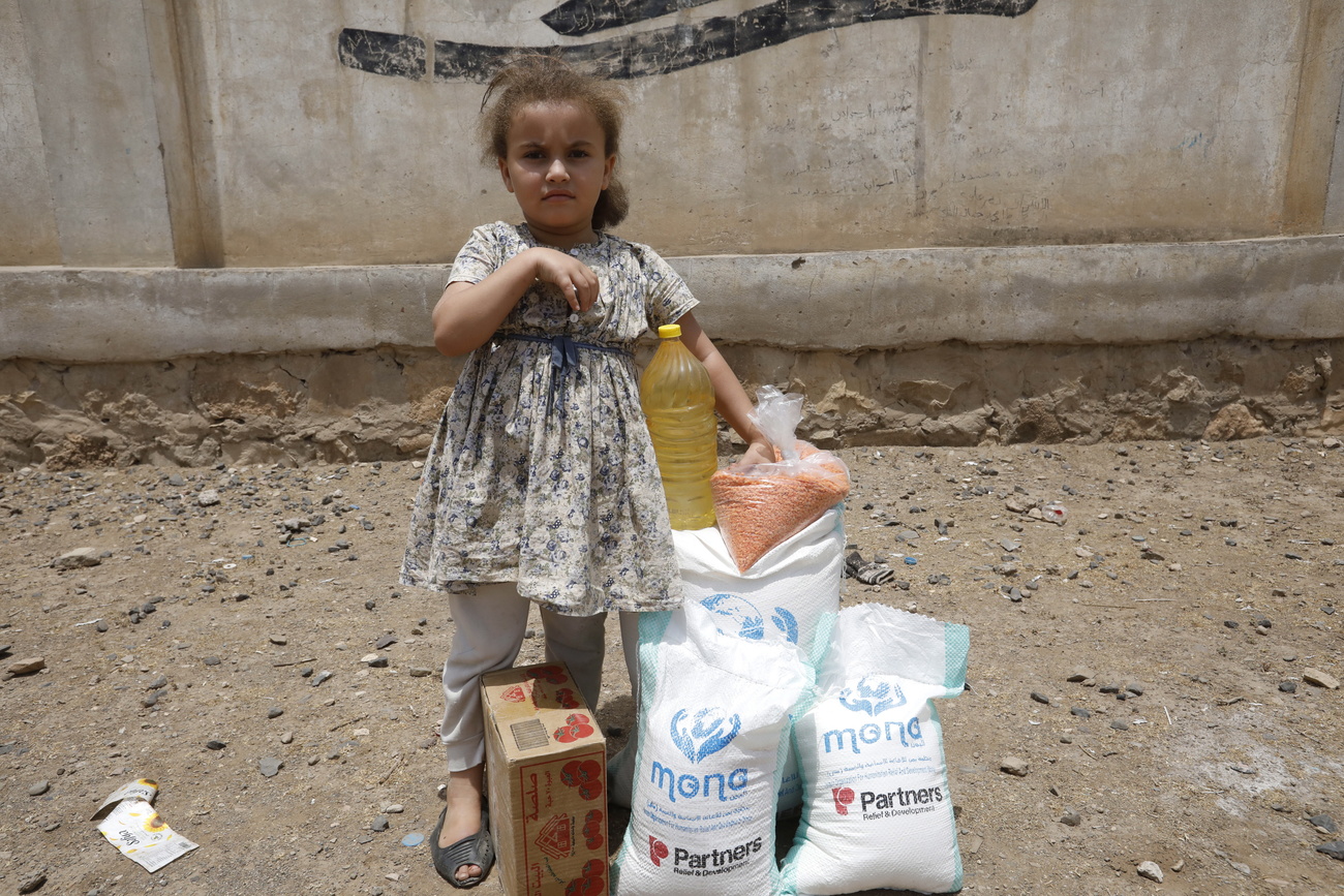bambina in piedi accanto a sacchi contenenti razioni di cibo