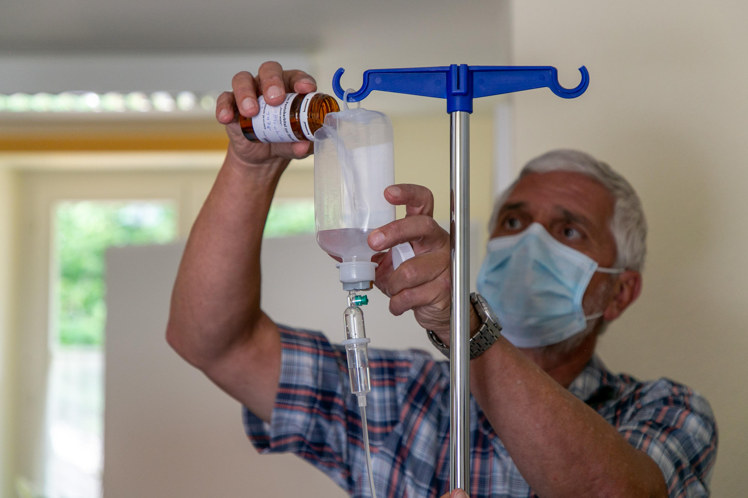 Un hombre introduce un medicamento en un recipiente para vía intravenosa