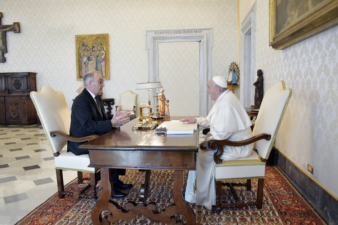 Ein Mann im Anzug sitzt mit dem Papst an einem Schreibtisch