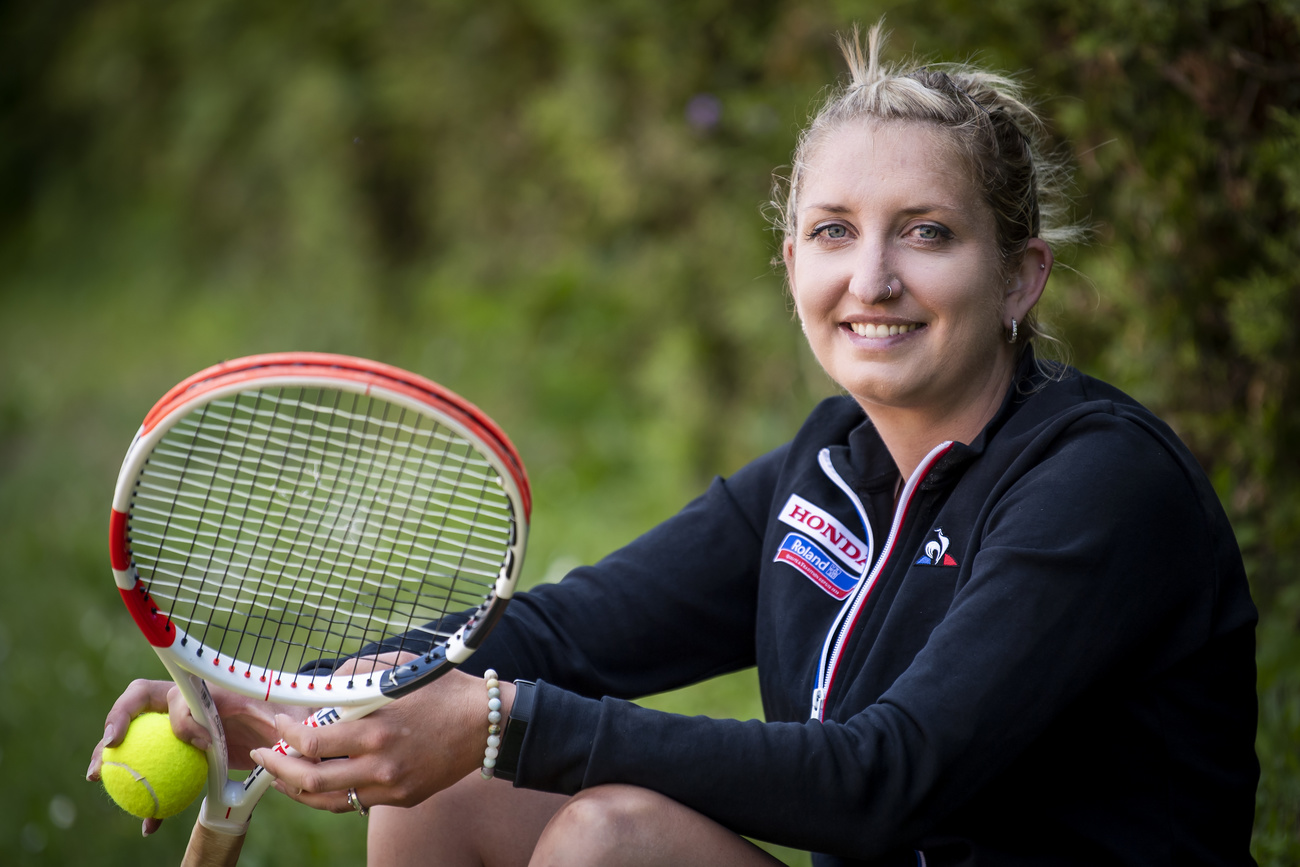 Un joueuse de tennis pose avec un balle et une raquette