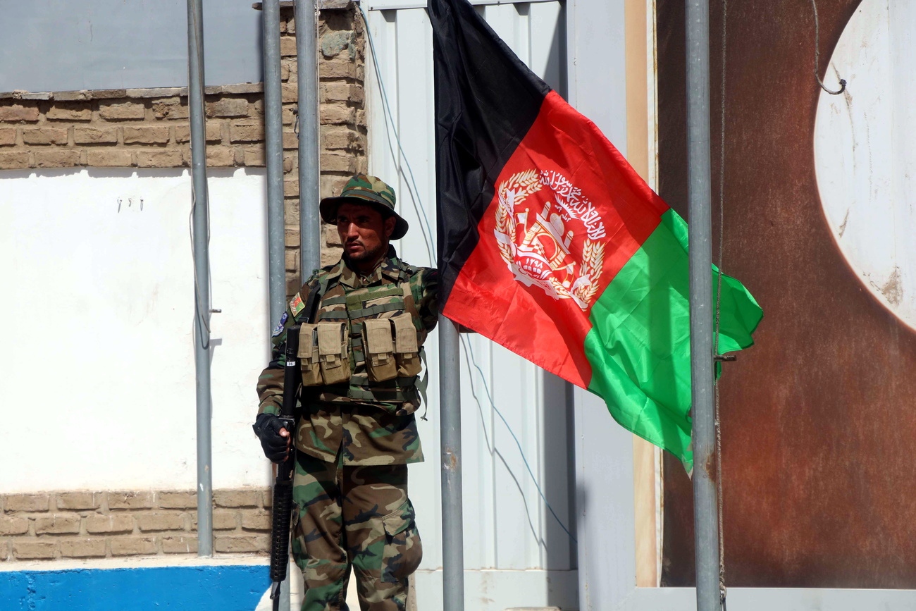 Un soldato dell esercito regolare afghano davanti a una bandiera del suo paese.