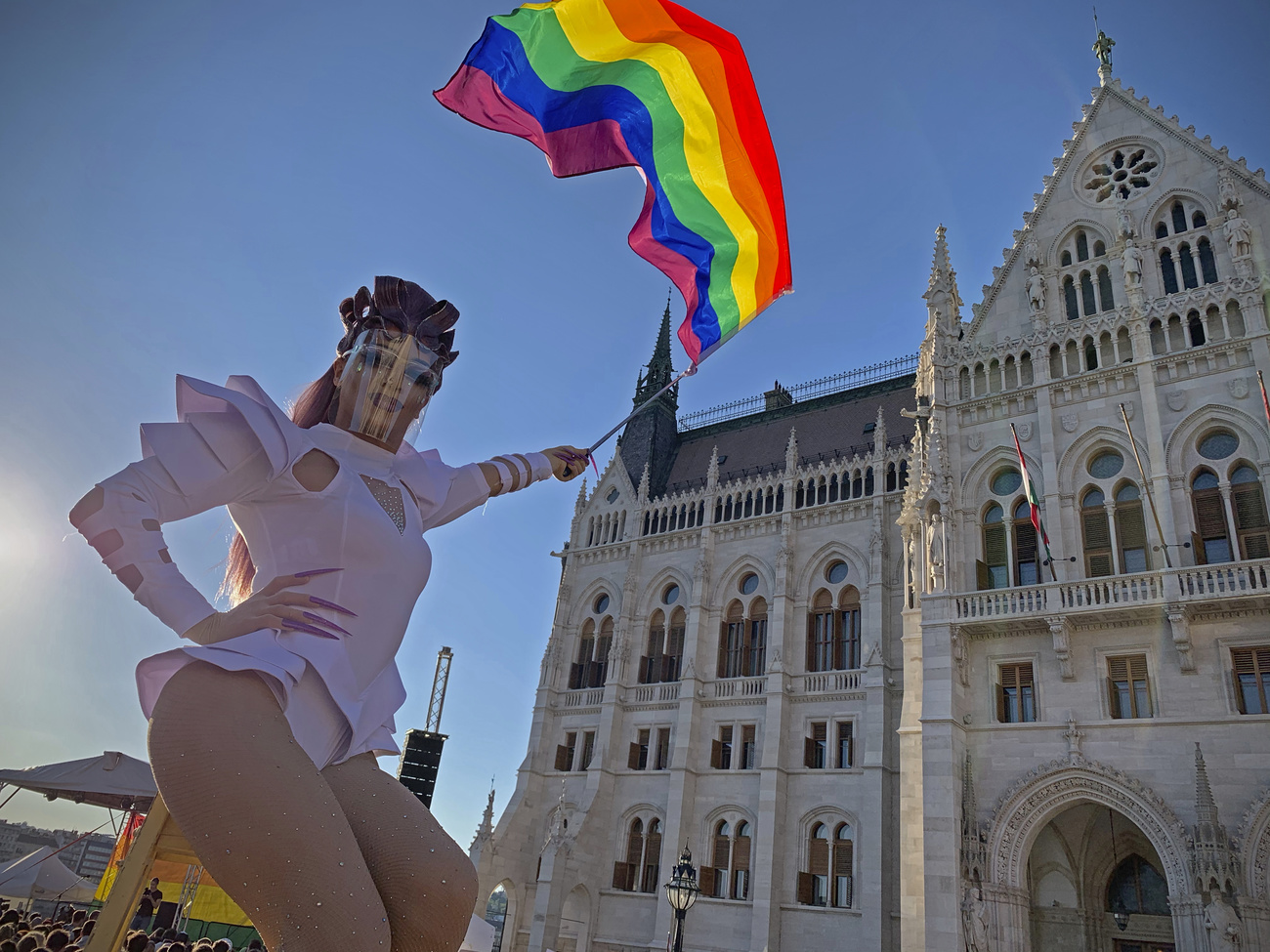 Una drag queen con una bandiera arcobaleno davanti al parlamento ungherese.