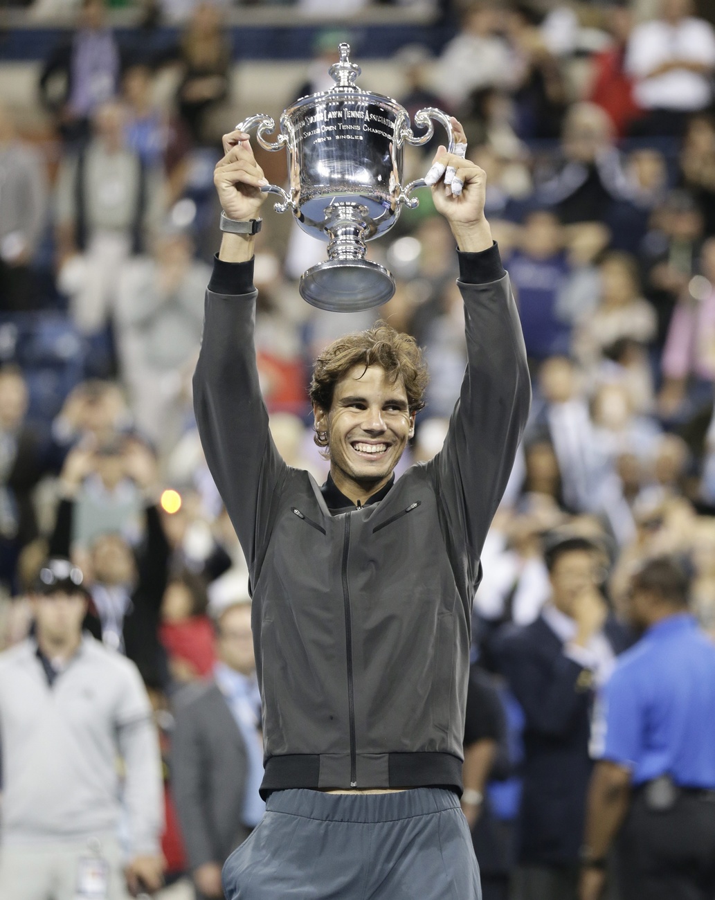 Joueur de tennis levant un coupe au-dessus de sa tête.