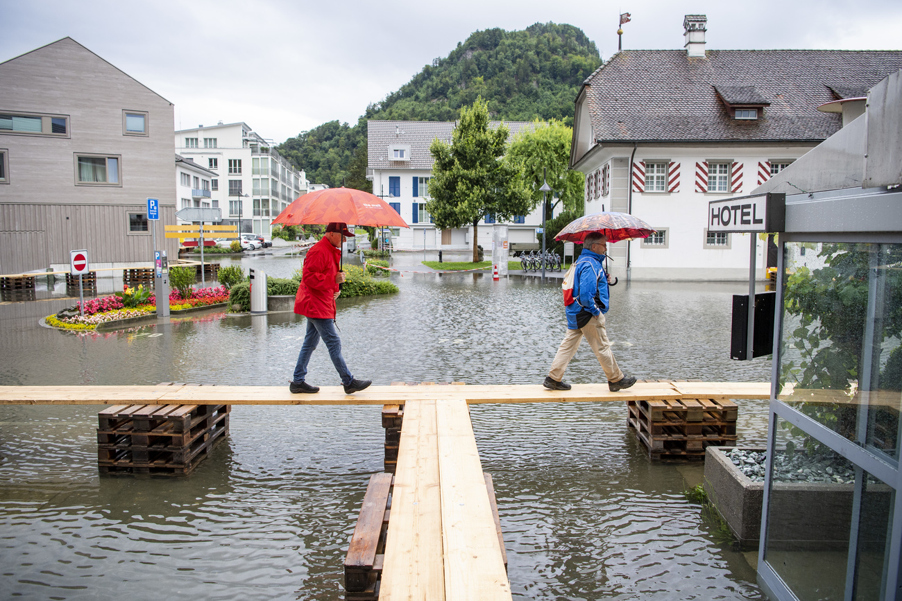 رجلان يمشيان على طريق مرتدل بسبب الفيضانات