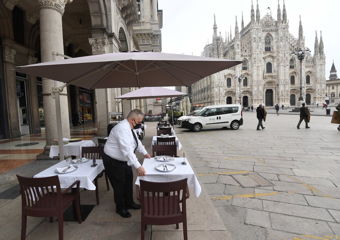 Cameriere prepara i tavoli del suo ristorante in Piazza Duomo a Milano.