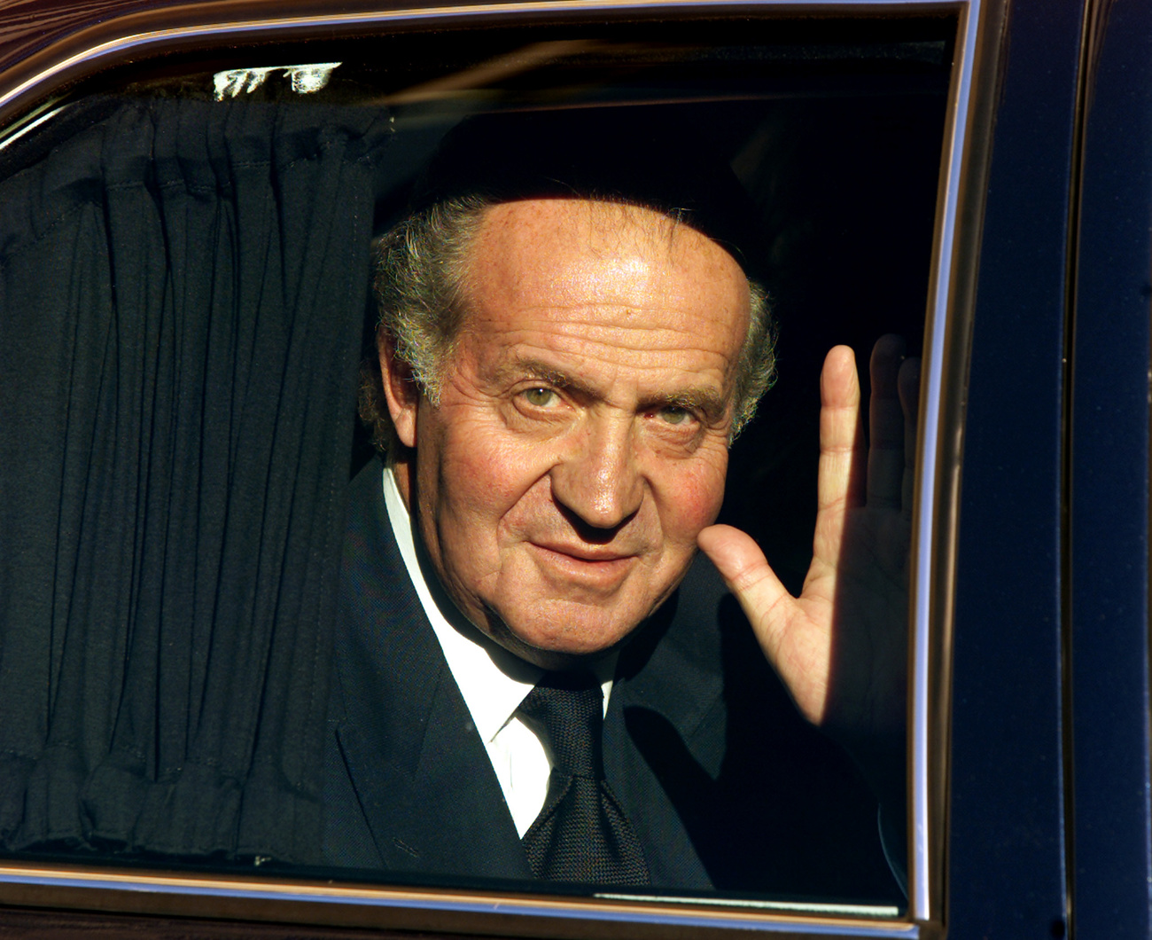 El rey Juan Carlos saluda desde el coche