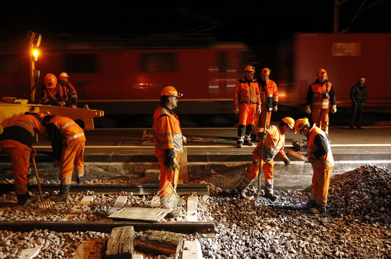 Operai alle prese con la posa di binari ferroviari.