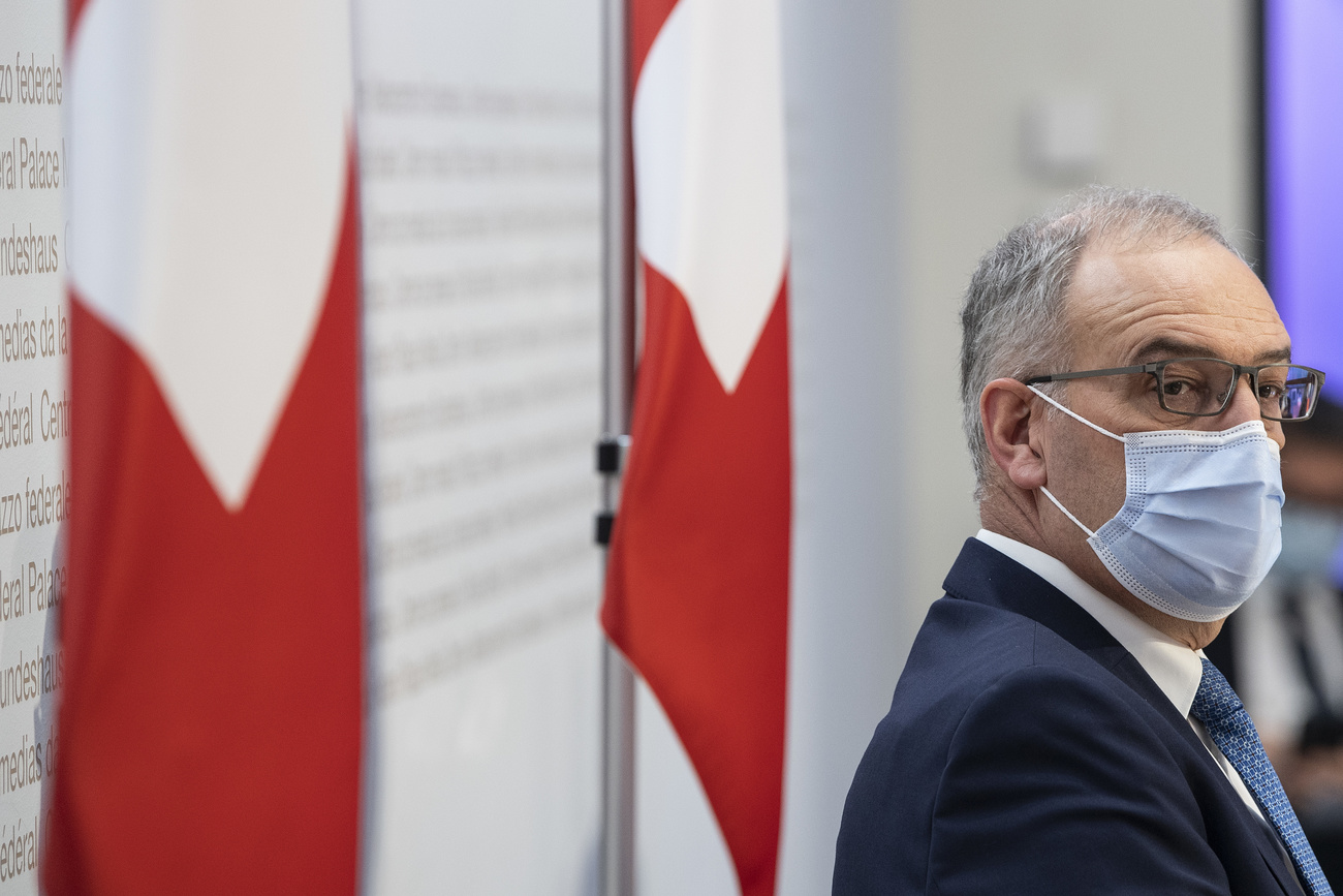 رجل يرتدي قناعا صحيا وفي الخلفية علم سويسرا