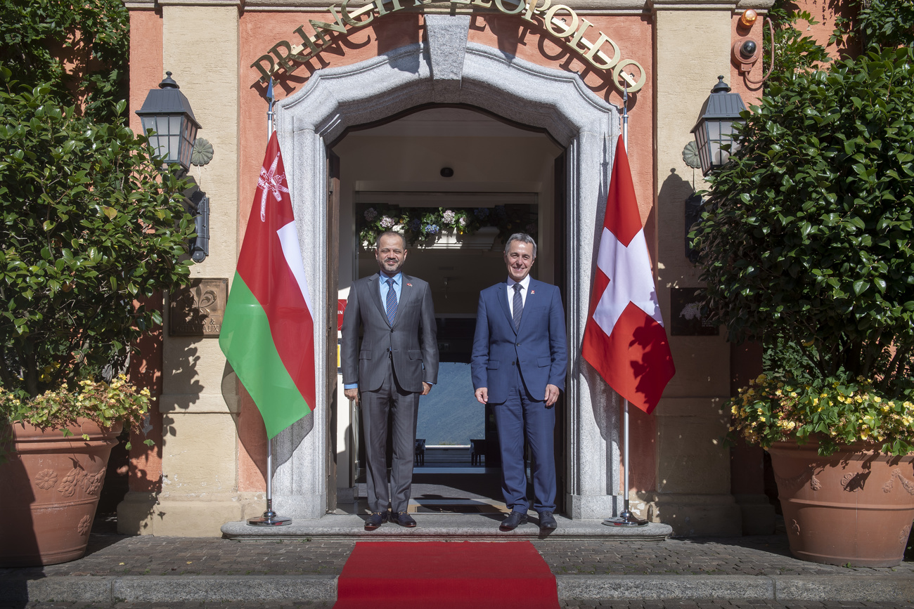 Foreign ministers of Oman and Switzerland posing in front of building with flags