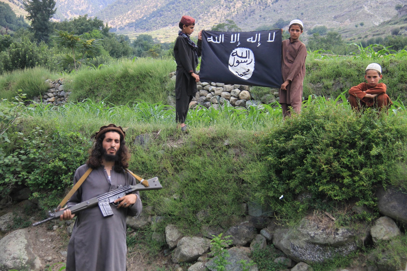 Due bambini reggono la bandiera dell ISIS mentre un uomo imbraccia un fucile.