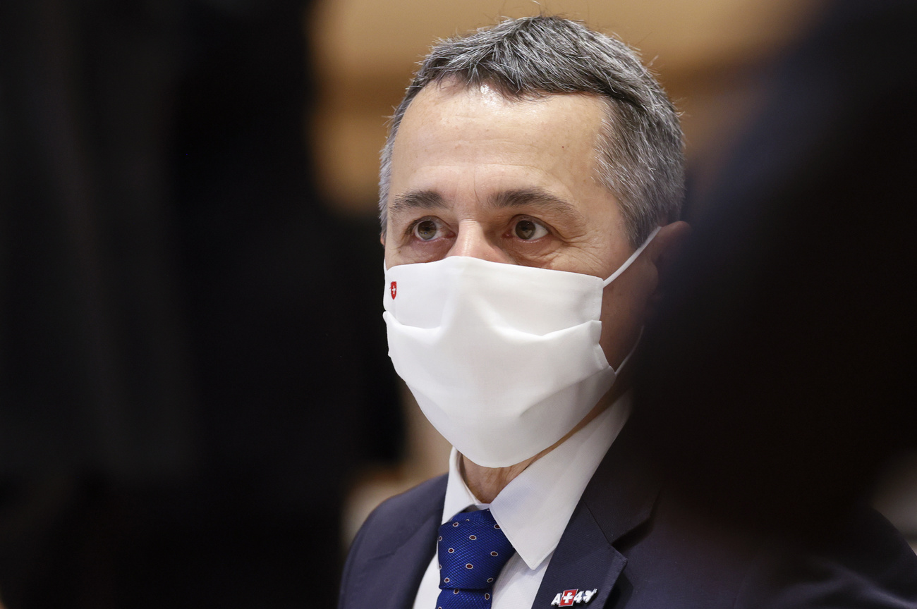 primo piano di ignazio cassis con mascherina bianca con piccola bandiera svizzeraricamata