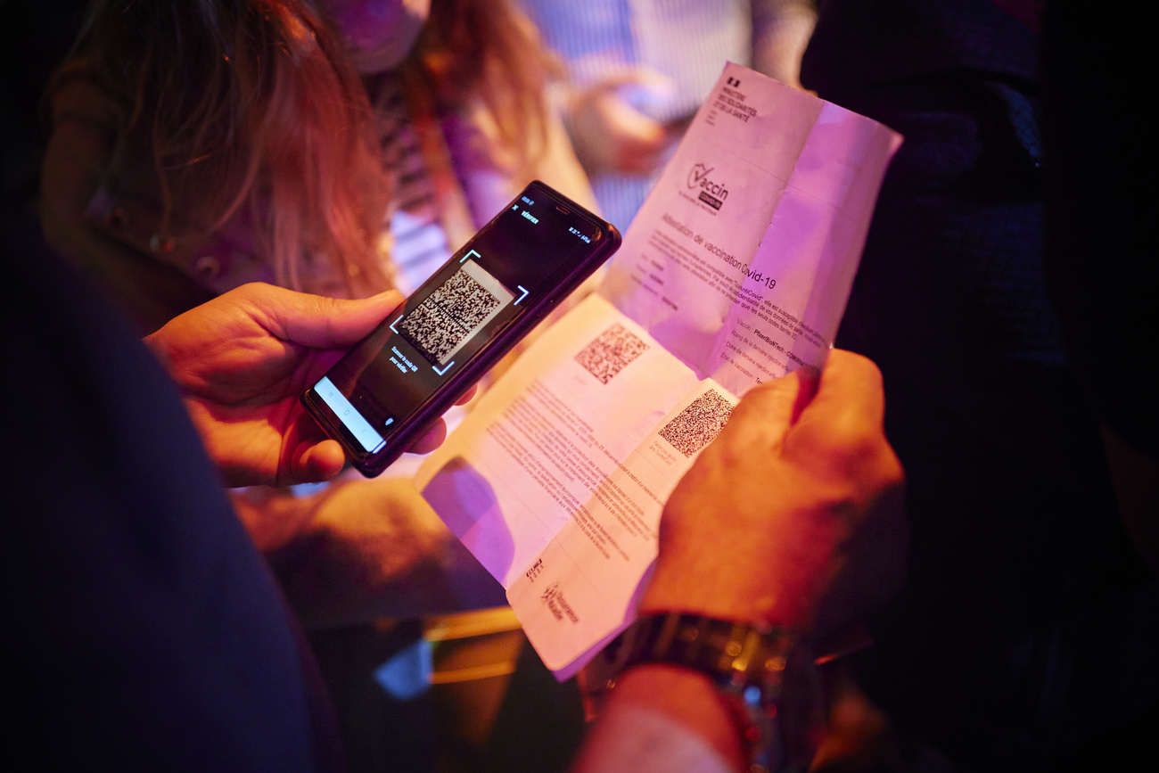 Las manos de una persona con un teléfono y un certificado COVID