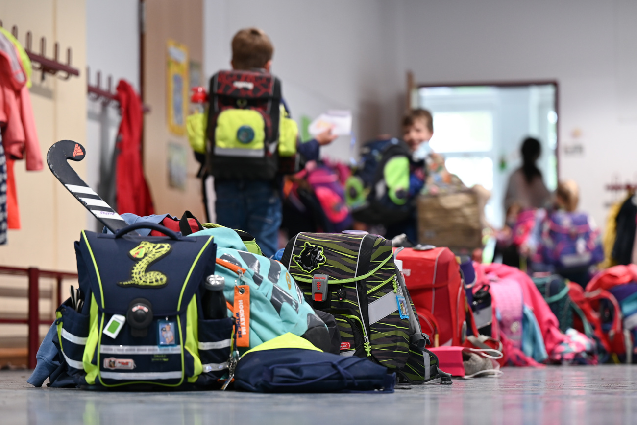 Cartelle scolastiche di bambini delle elementari posate per terra.