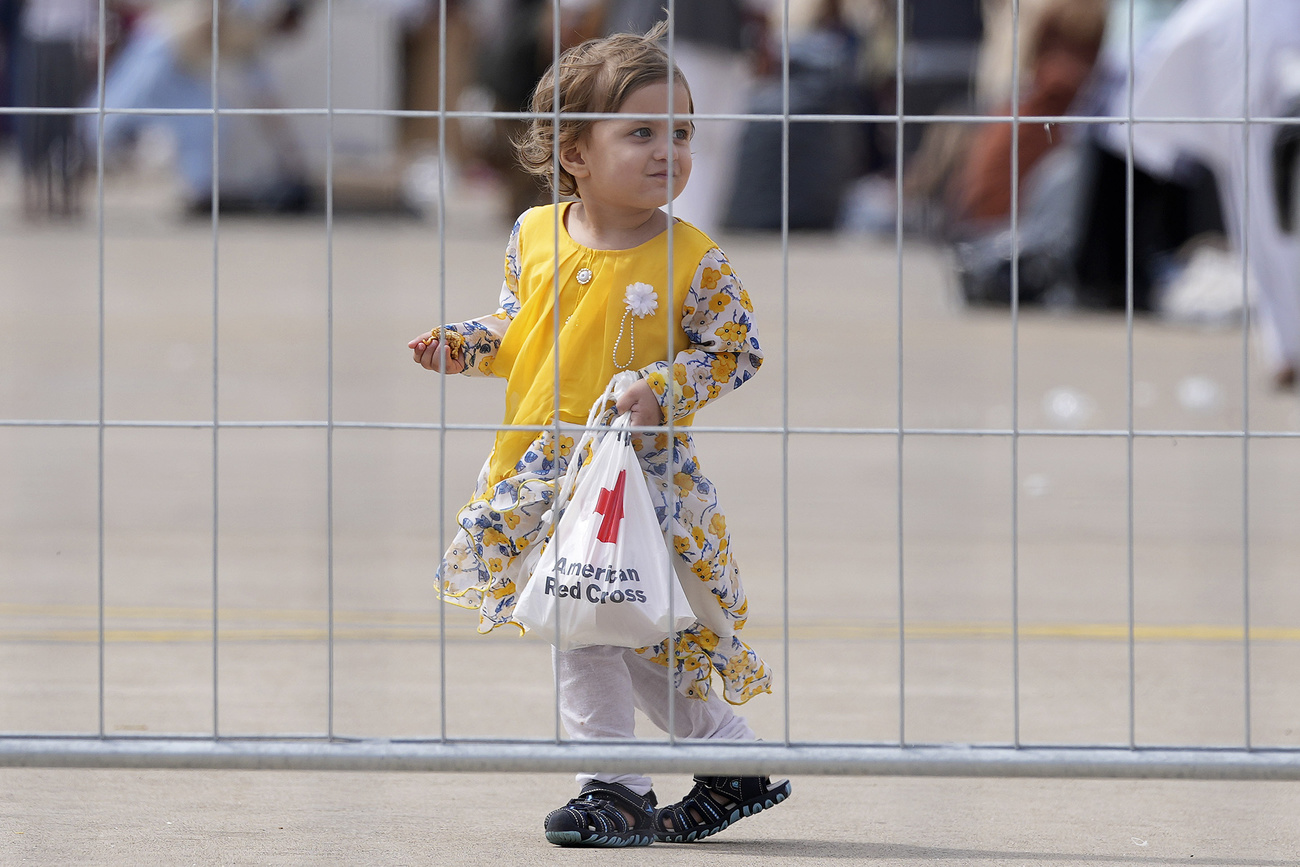 bambina vestita di giallo tiene una borsa di plastica della croce rossa in mano