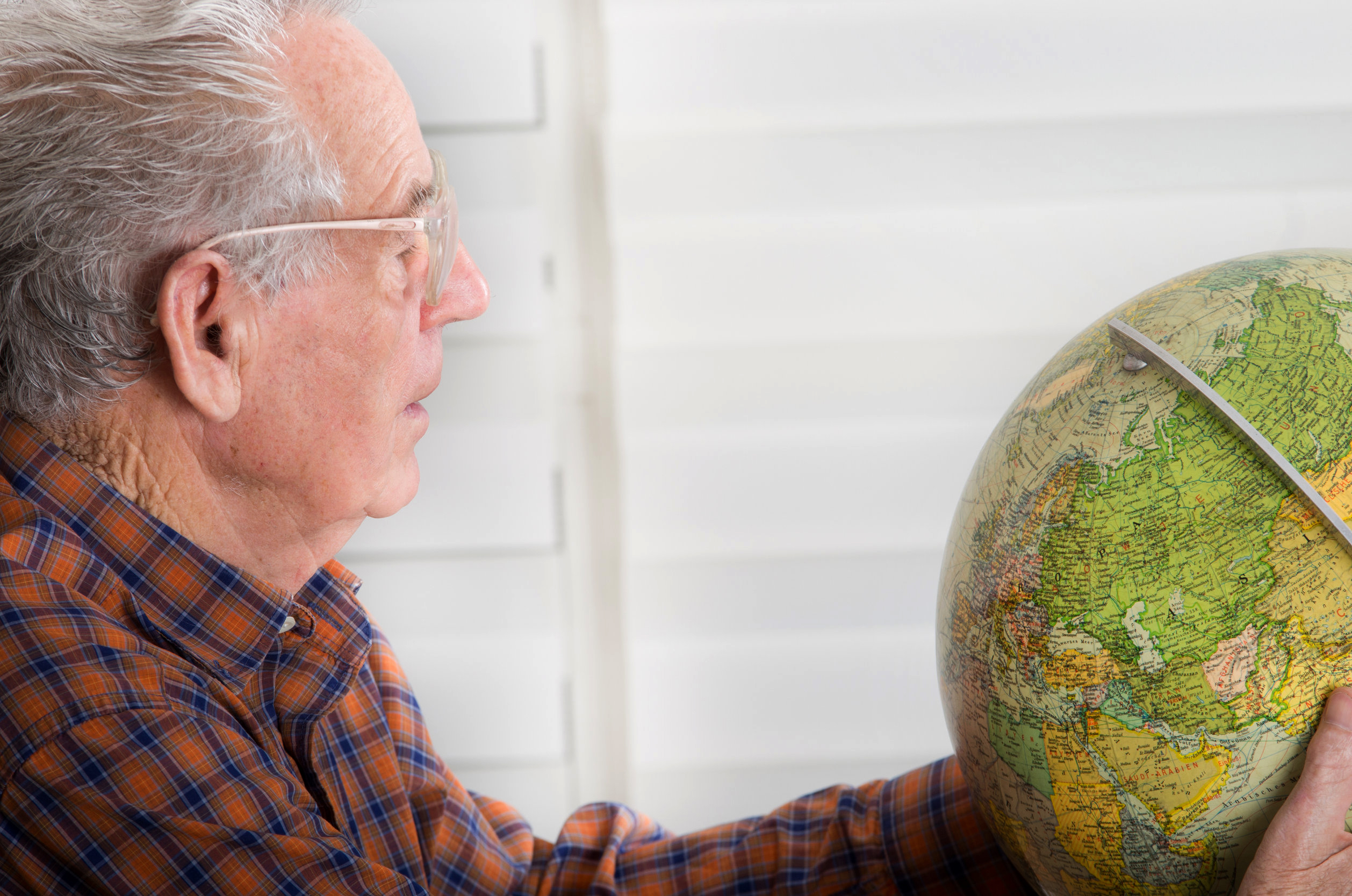 Un vieux monsieur regarde une mappe monde