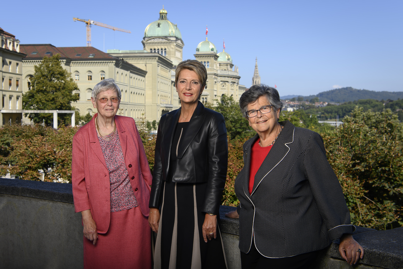 ثلاث نساء في صورة تذكارية وفي الخلفية مبنى القصر الفدرالي في برن