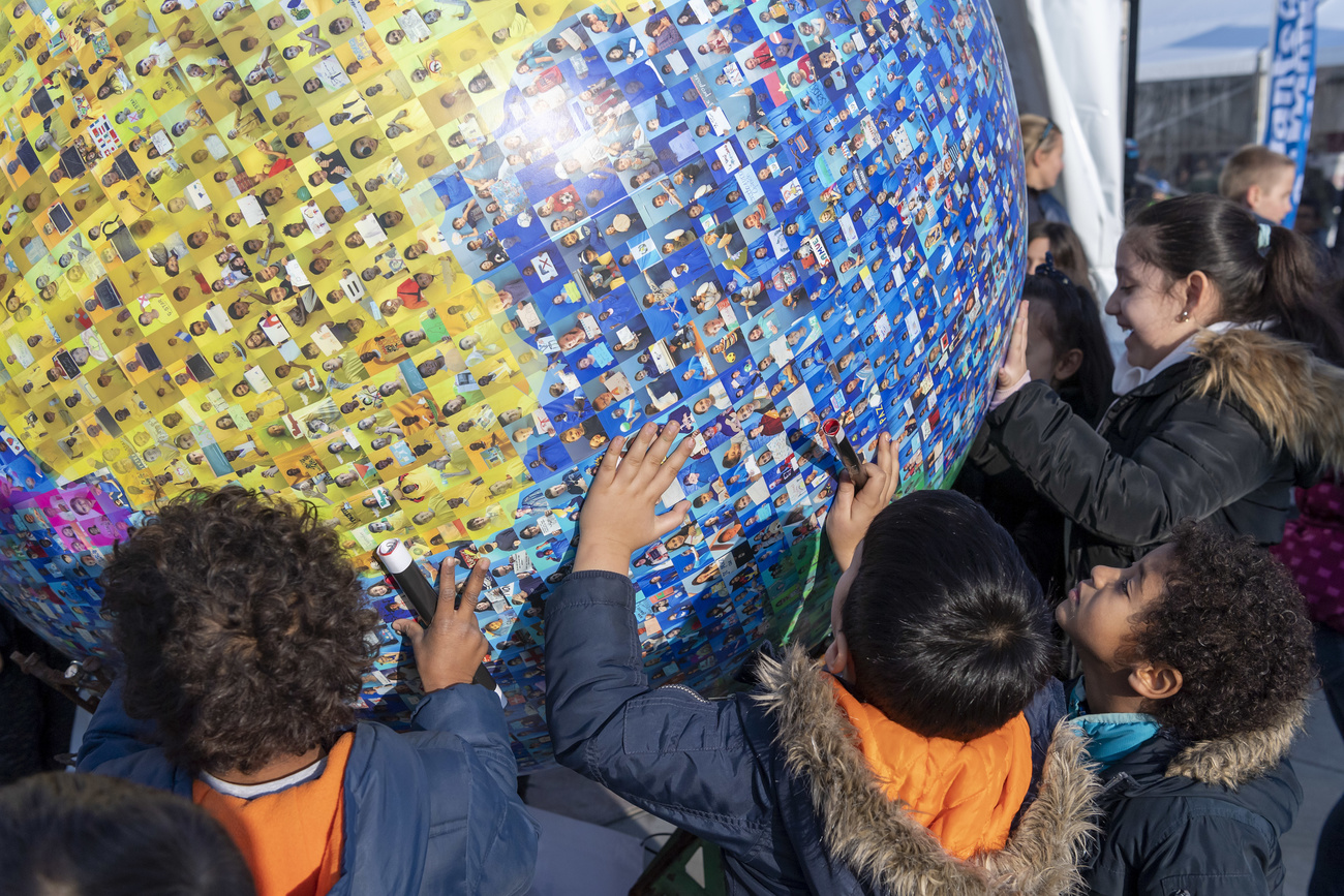 Children standing in front of globe with photos of children from around the world