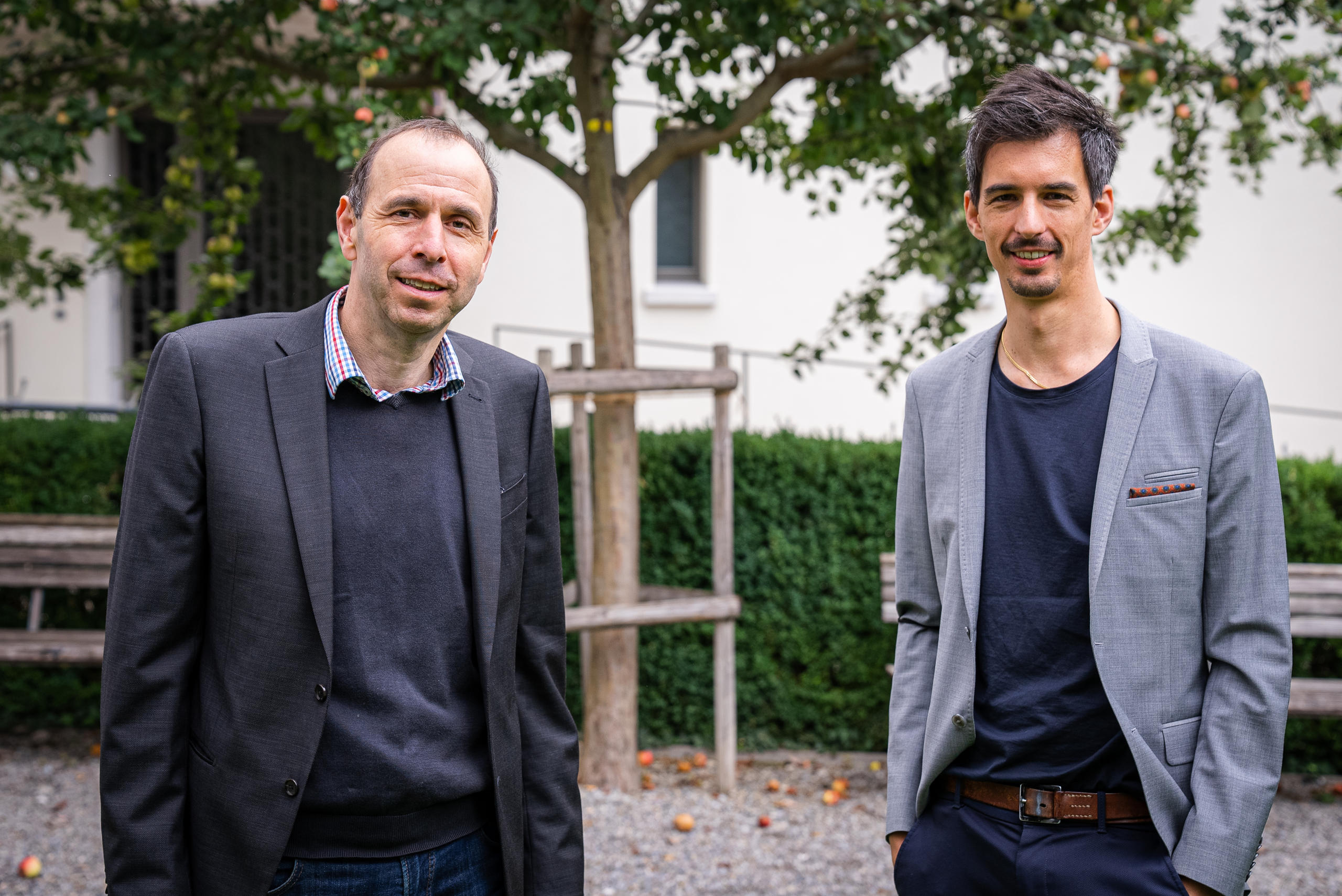 Deux hommes posant devant un arbre.