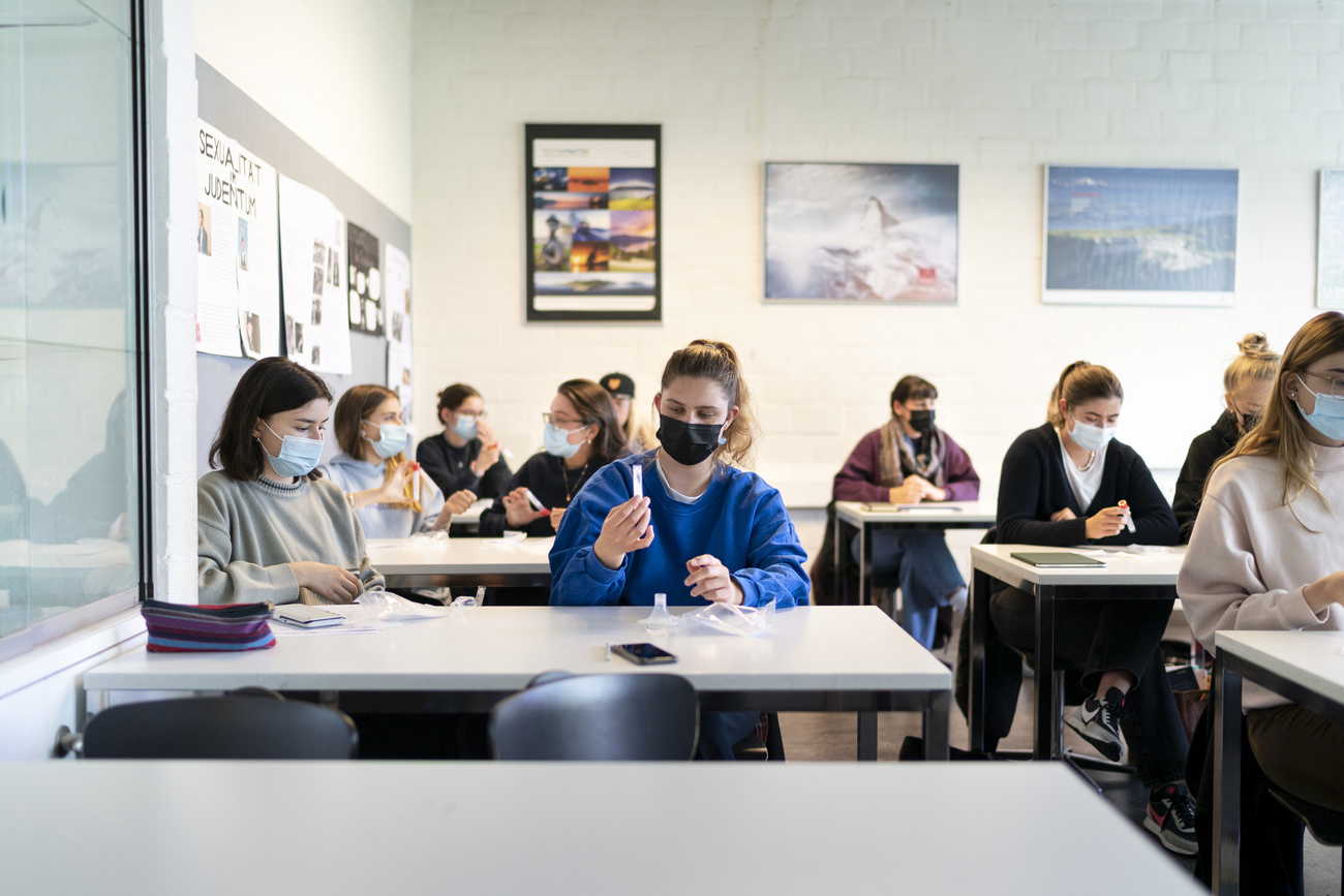 Studenti in aula mentre prelevano la saliva per il test.