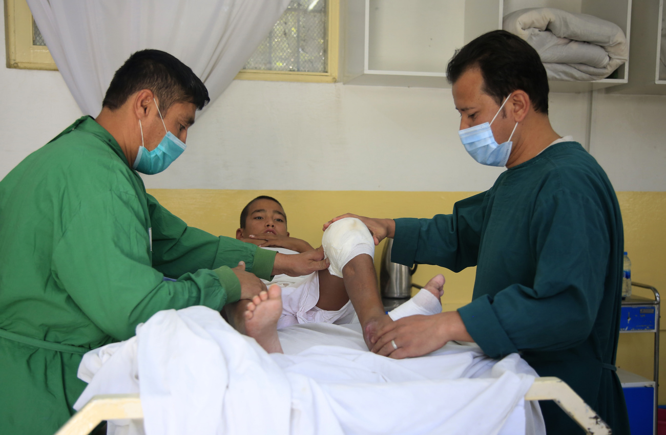 رجلان يُعالجان صبيا داخل مركز صحي في أفغانستان