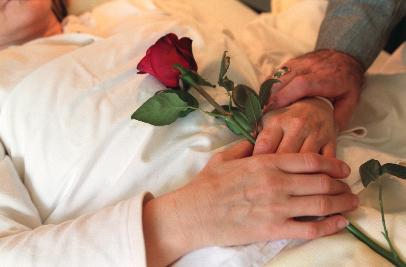 Una persona acostada en una cama con una flor entre las manos