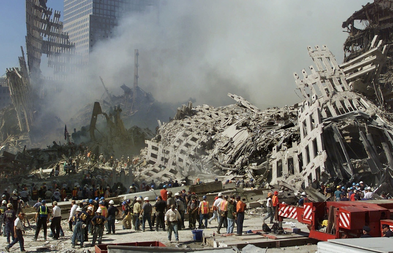 在2001年9月13日星期四这天拍摄的照片里，纽约世贸中心废墟依然冒着浓烟，救援人员仍在继续寻找幸存者。