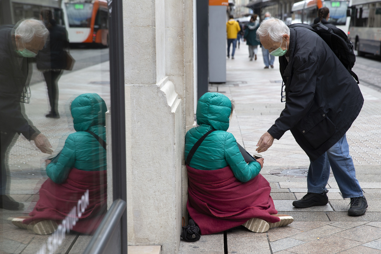 Homme donnant un pièce à une mendiante dans la rue.