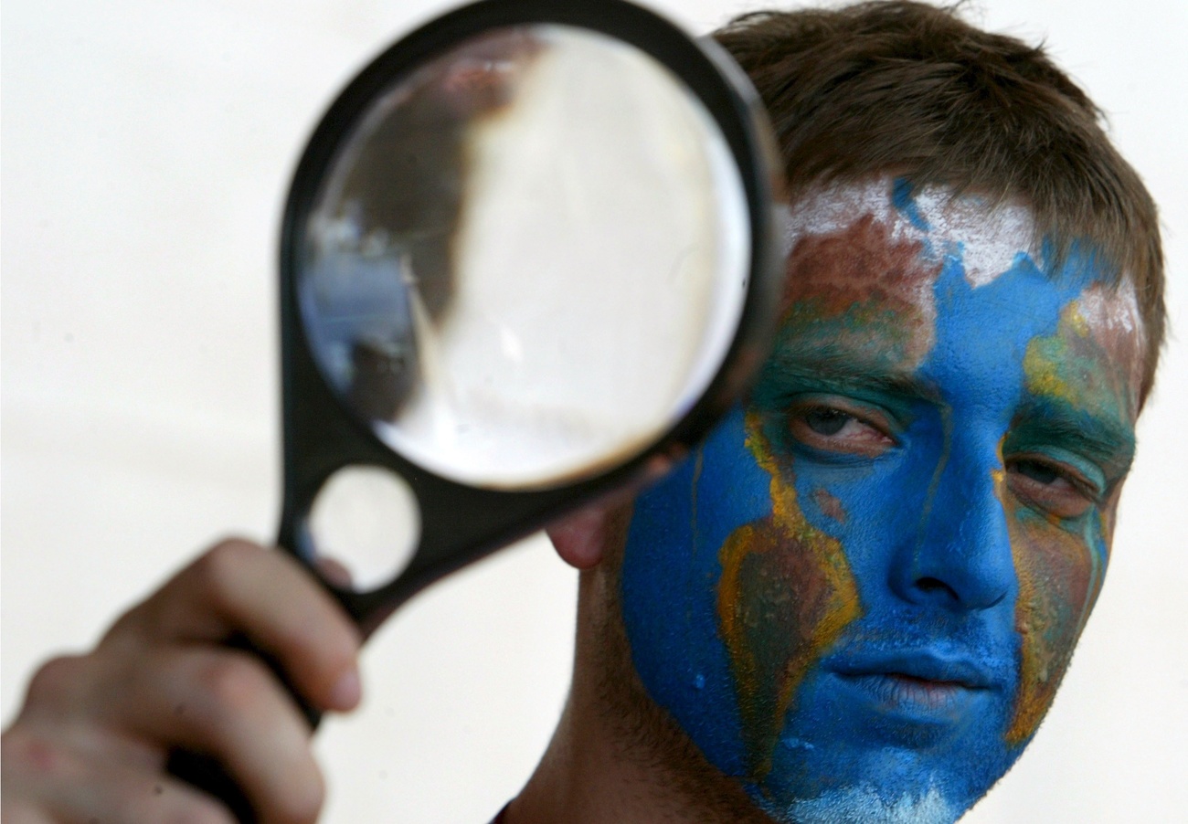 man with earth painted on his face, looking glass