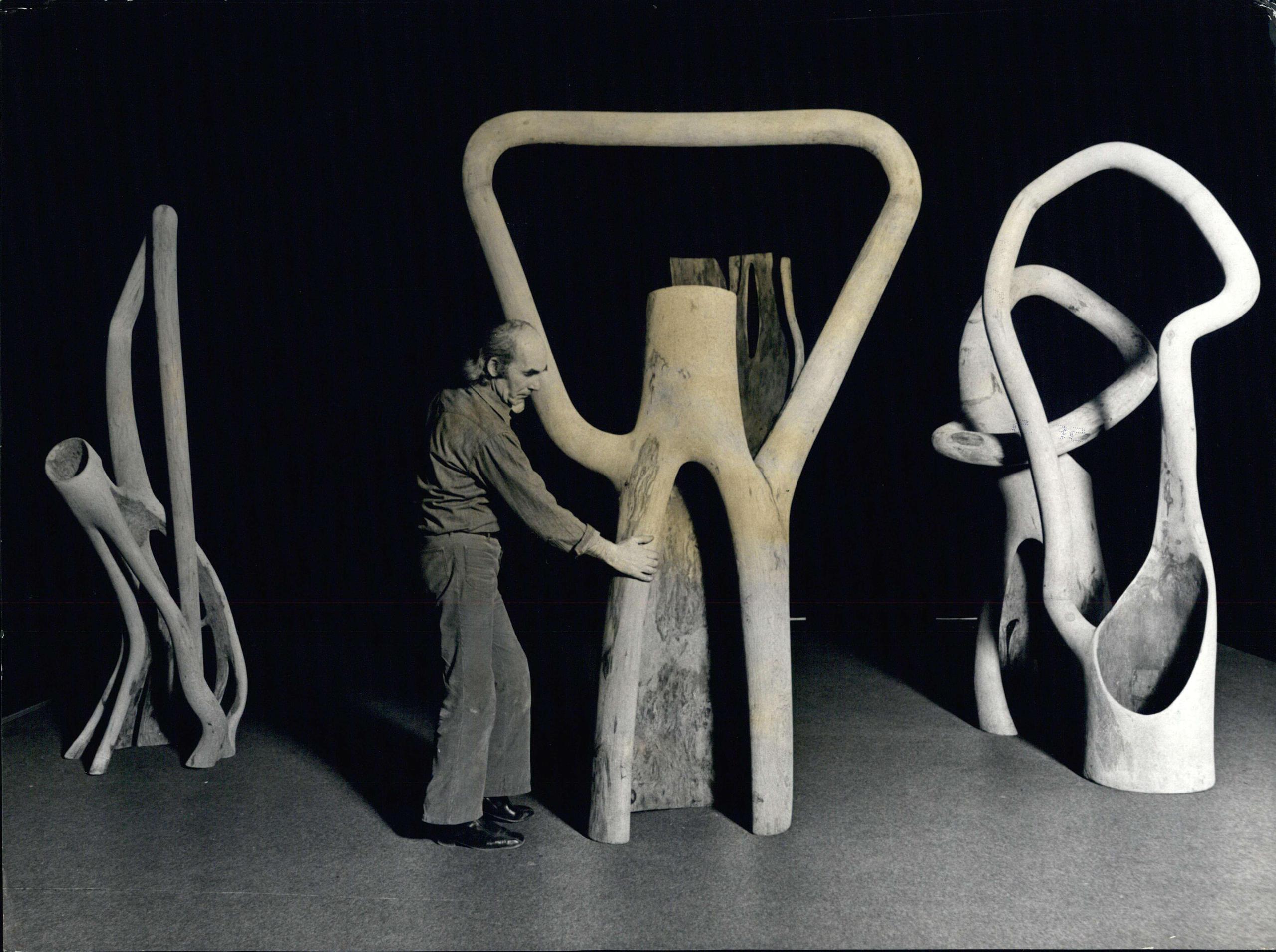 Un uomo mostra delle sculture ricavate da tronchi incavati e altri frammenti d alberi
