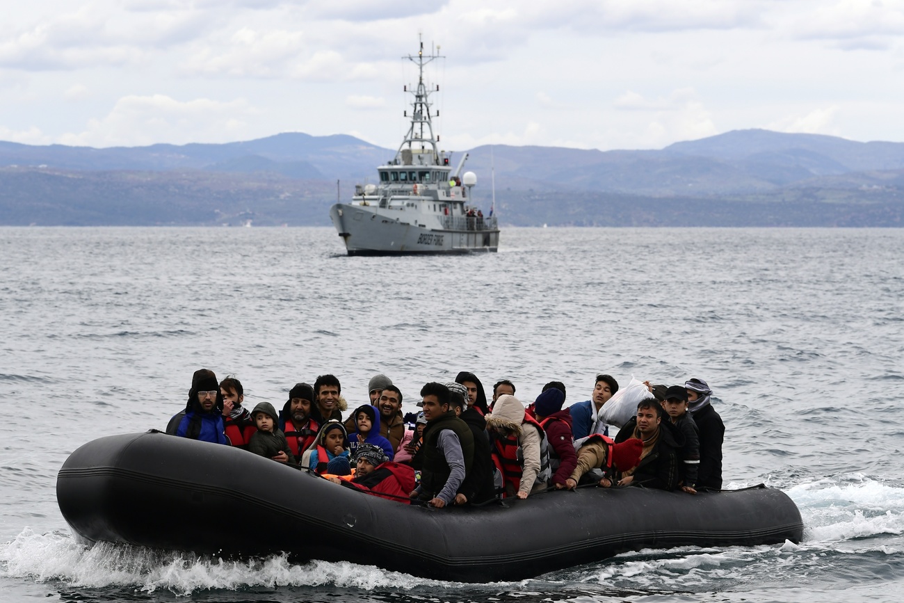 Grupo de migrantes en una balsa inflable y embarcación de la guardia fronteriza