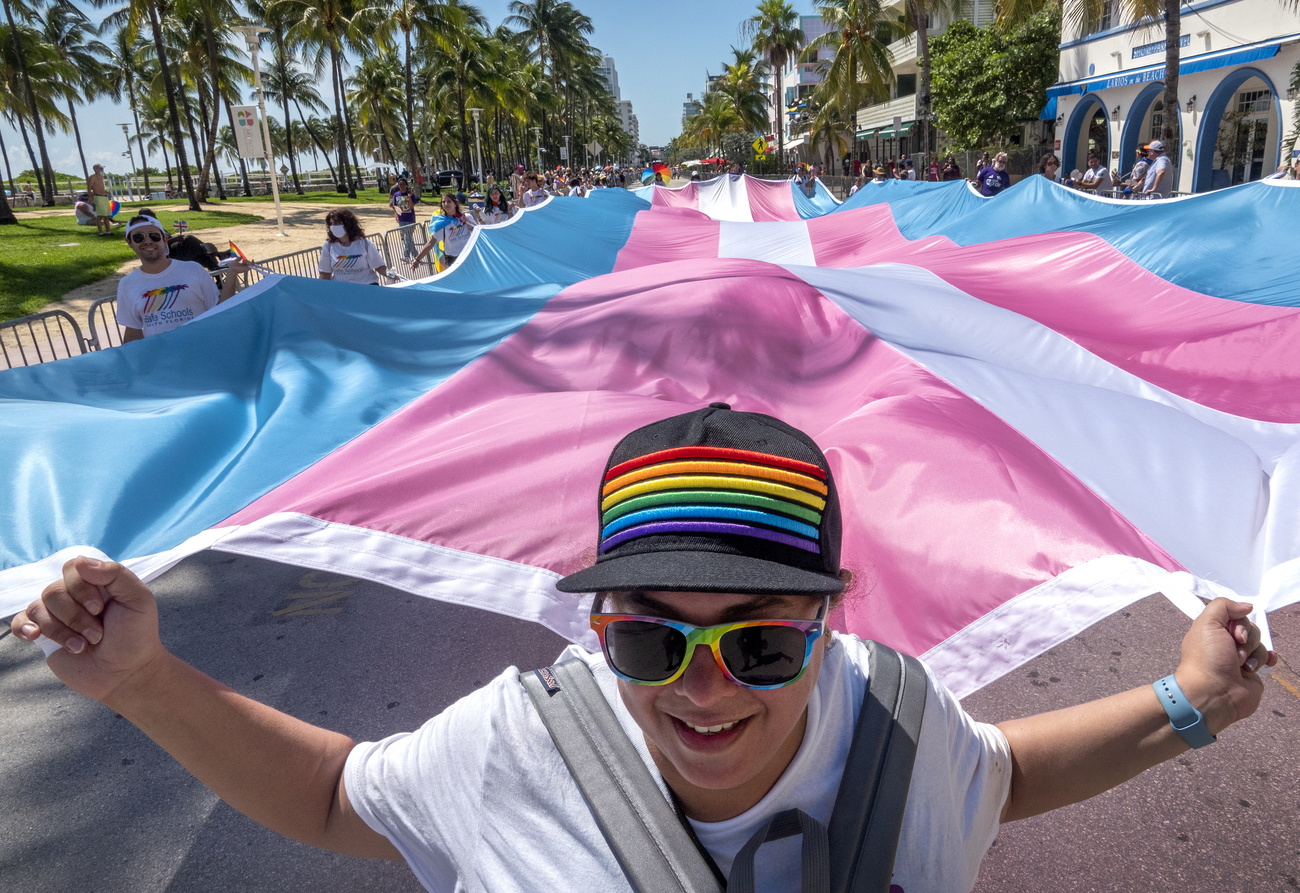 bandiera transgender portata da persona con cappellino con colori arcobaleno
