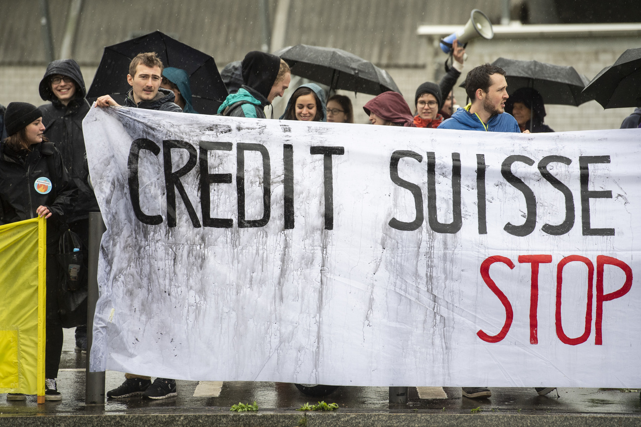 striscione tenuto da diverse persone con scritta credit suisse stop
