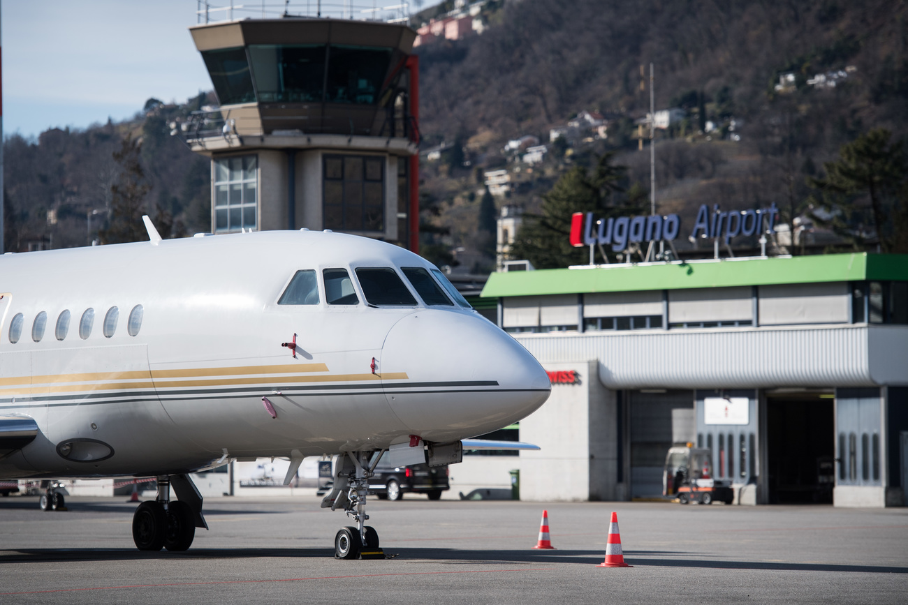 aereo parcheggiato al suolo e dietro scorcio dello scalo di lugano