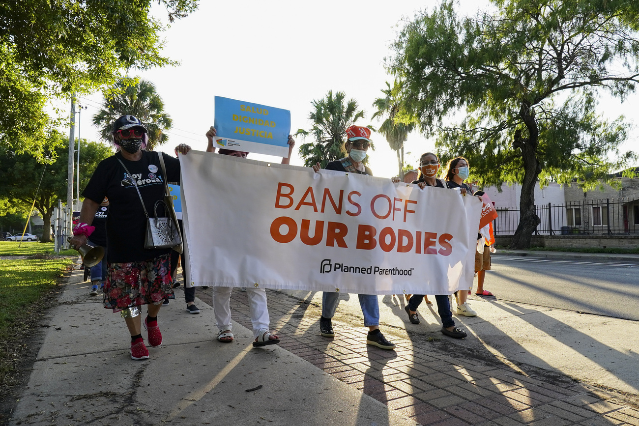 gruppo di donne marcia con cartello con scritta in inglese