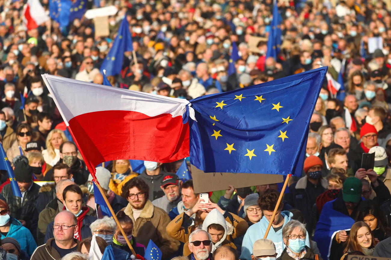 Una banciera polacca legata a una europea in nella piazza principale di Cracovia gremita di gente.