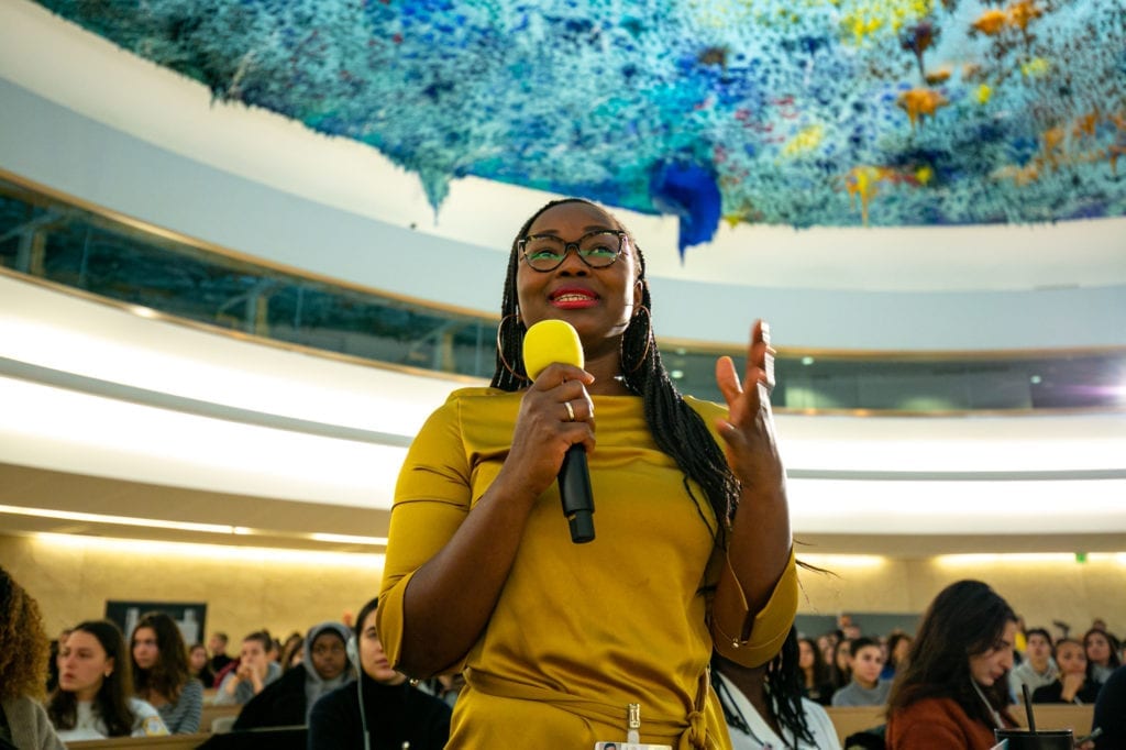 Girl with yellow Shirt speaks into a microphone