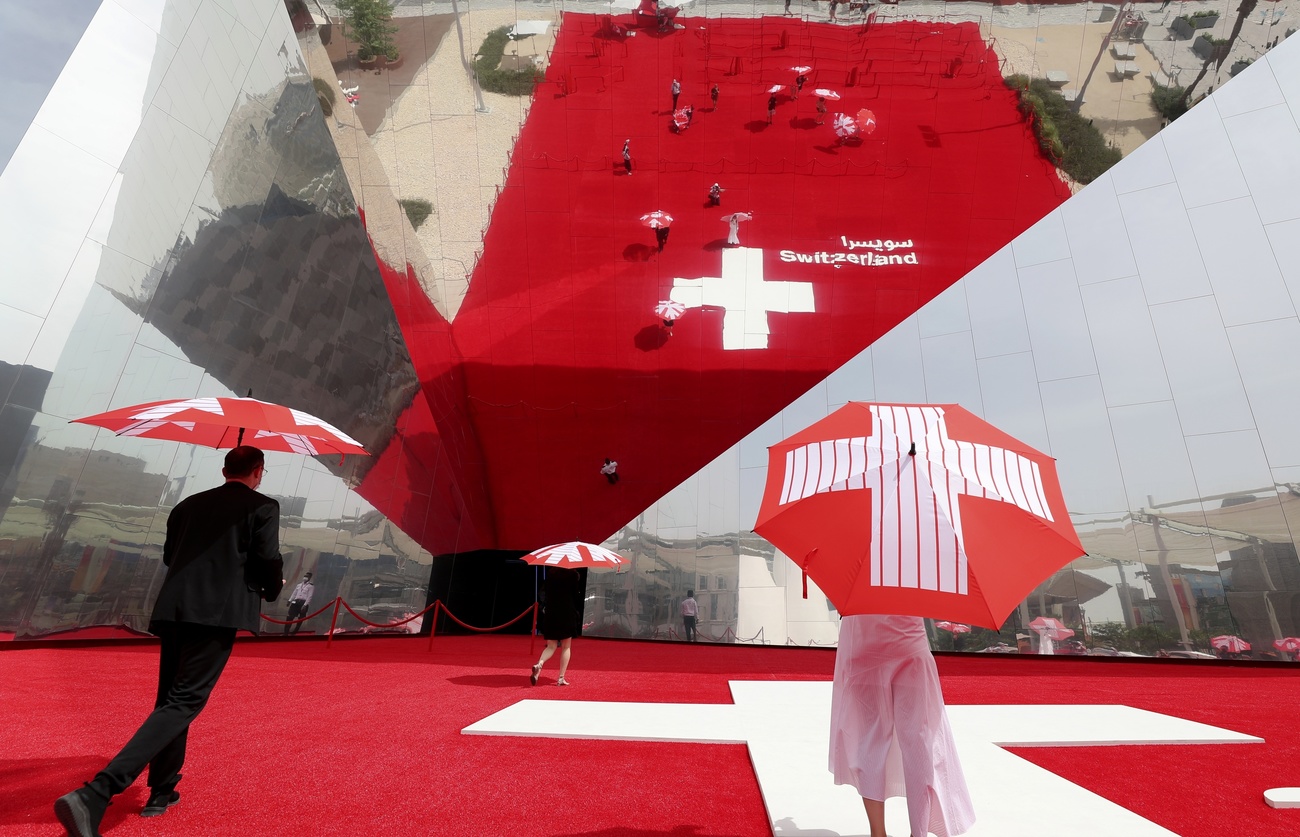 due persone con ombrello con bandiera svizezra e su tappeto con bandiera svizezra