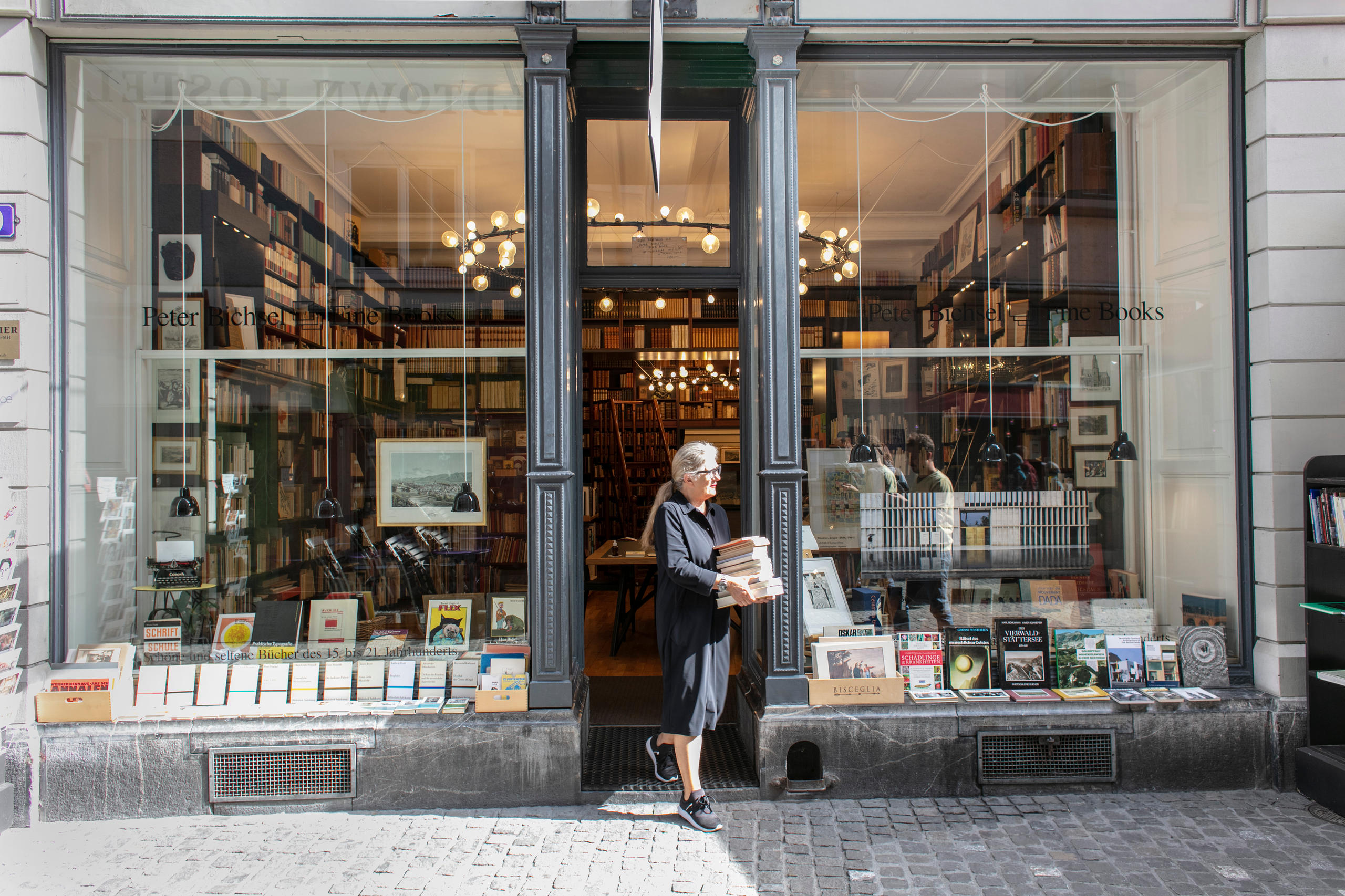 Mujer con libros en la entrada de una librería