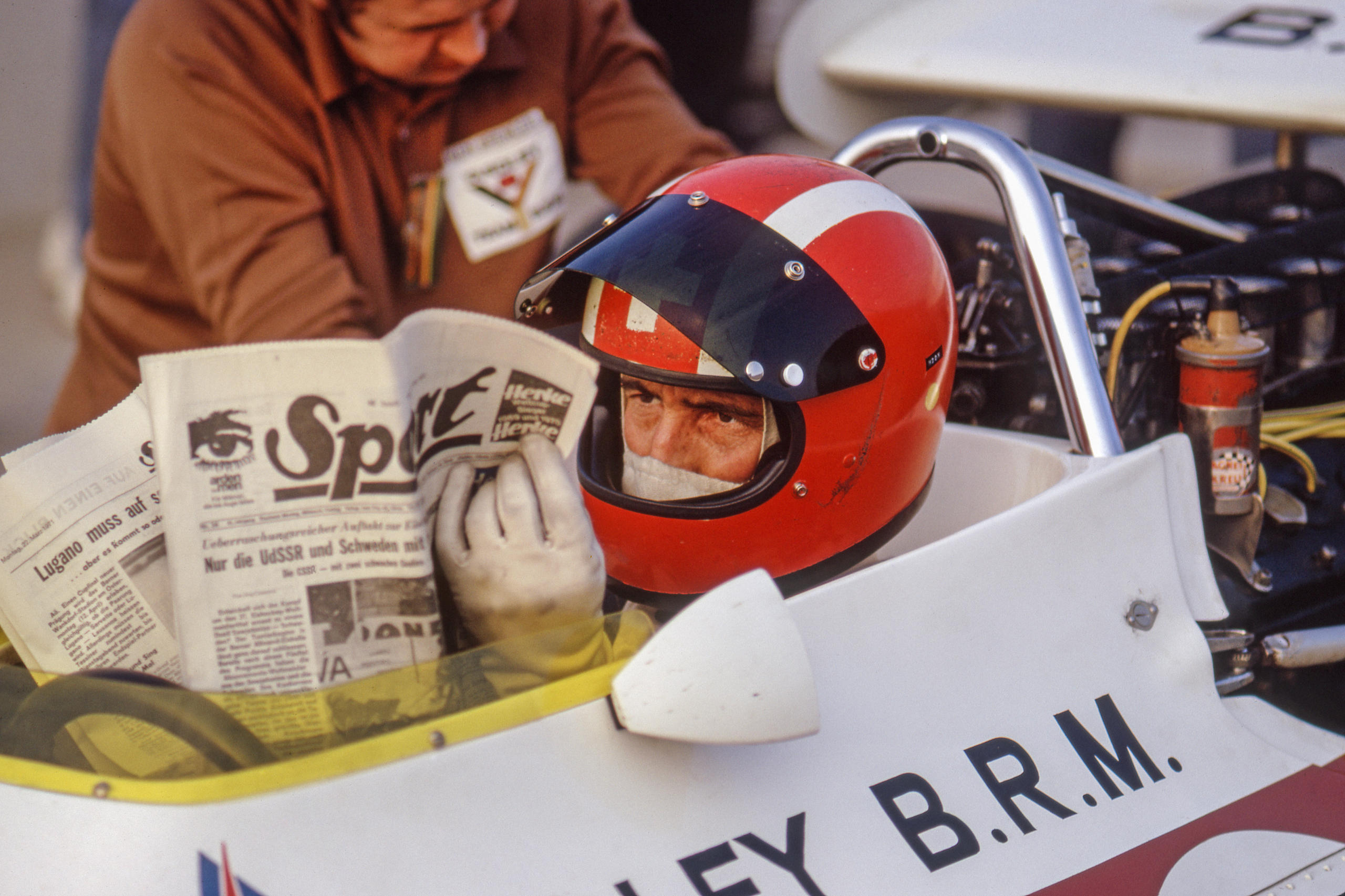 Pilote de course lisant un journal dans son cockpit.