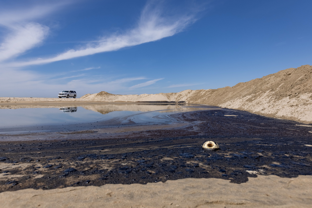 Spiaggia completamente nera a causa del petrolio fuoriuscito.