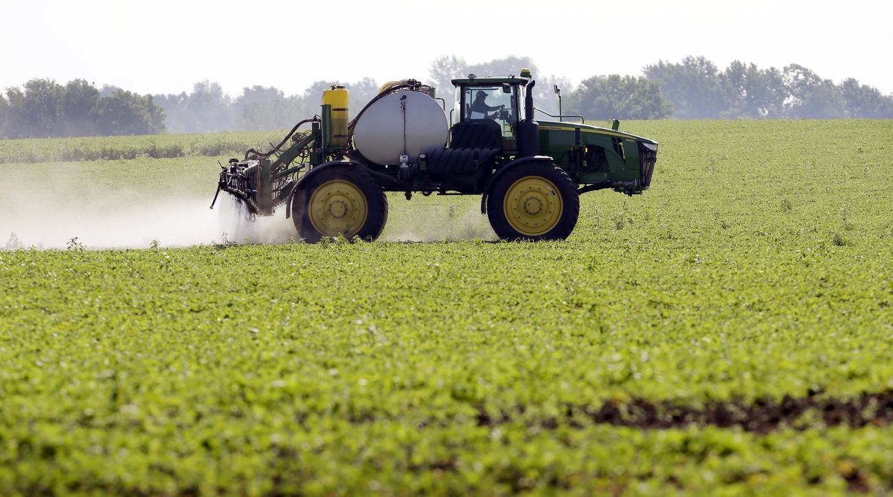 Trattore con irrigatore spruzza un prodotto fitosanitario in campo aperto