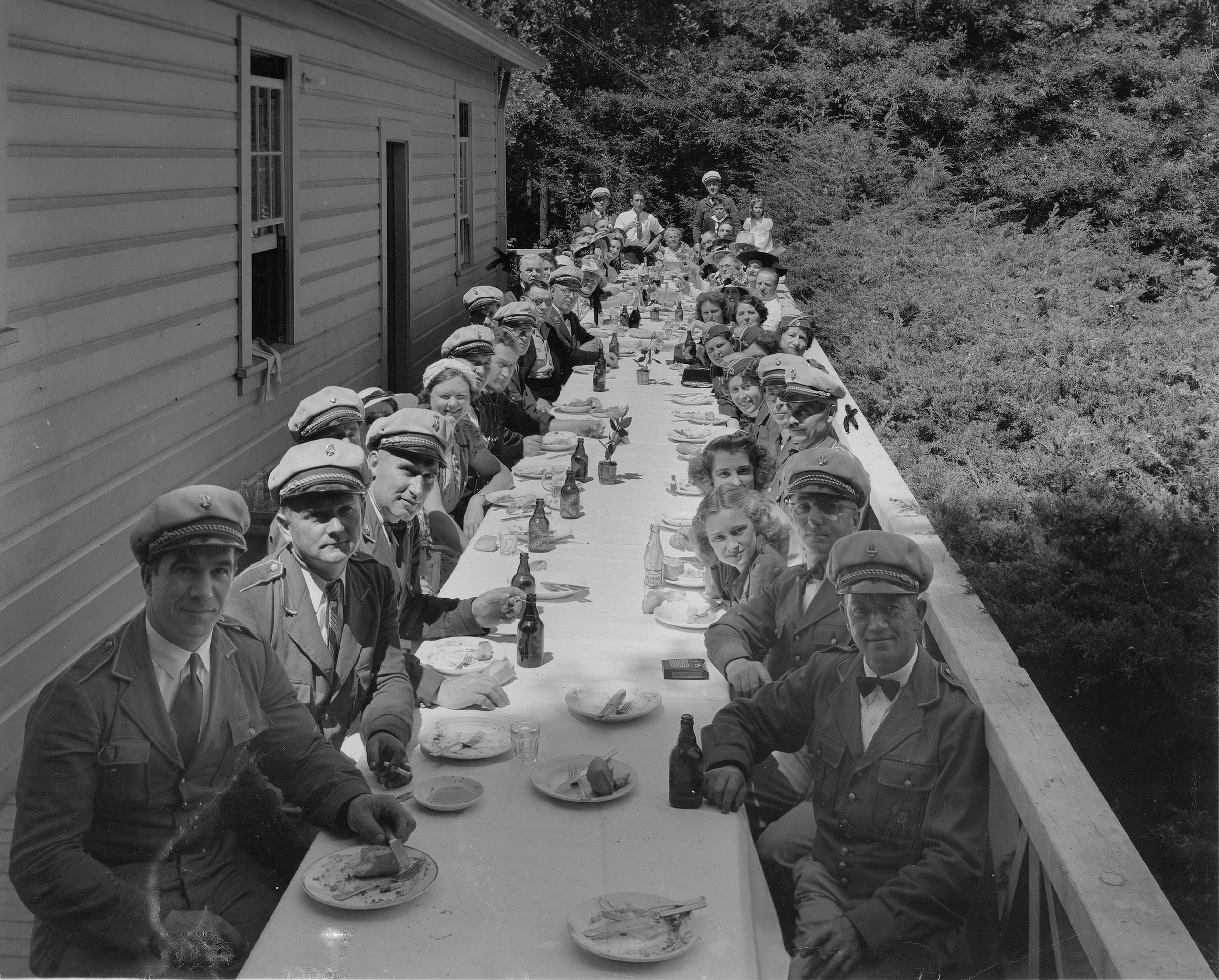 persone sedute a un lungo tavolo in una foto in bianco e nero