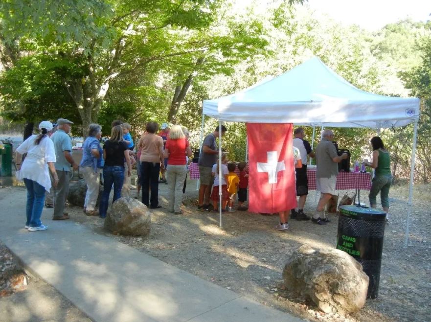 gente accanto a un gazebo con la bandiera svizzera