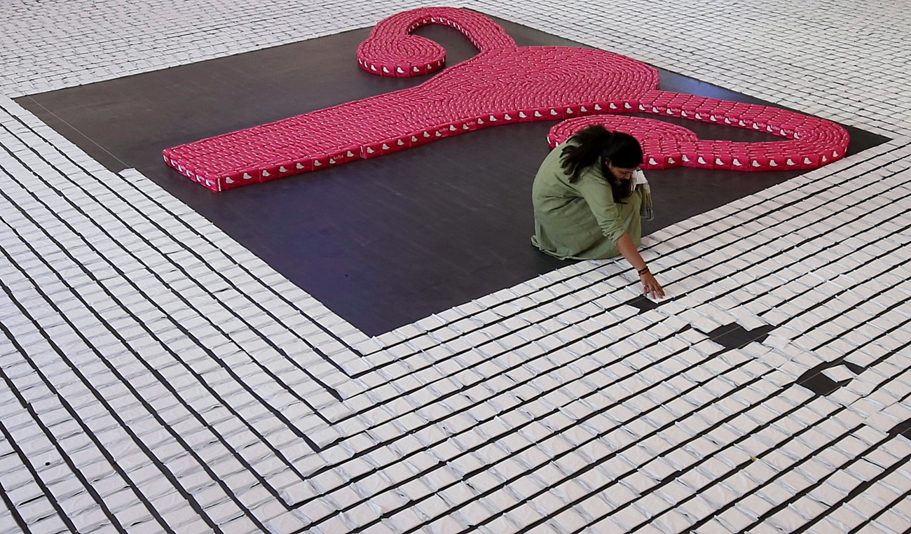 Una señora forma con paquetes de tampones un dibujo de un útero