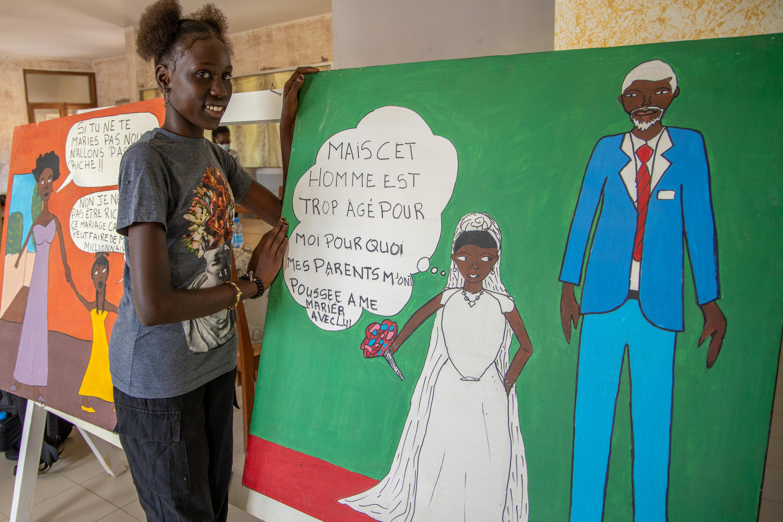 Una joven posa delante de una pintura que denuncia los matrimonios forzados